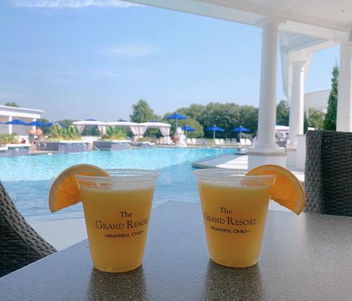 Two refreshing orange drinks with a slice of orange sit on a table by a pool at The Grand Resort in Warren, Ohio.