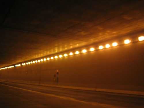 A dimly lit tunnel with a smooth ceiling and evenly spaced lights along the walls.