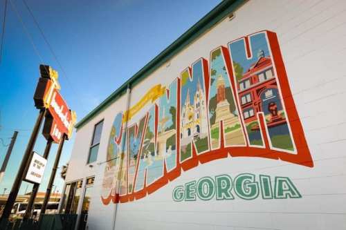 Colorful mural of "Savannah, Georgia" on a building, showcasing local landmarks and vibrant designs.