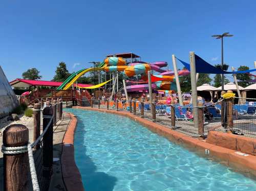 A vibrant water park featuring colorful slides, a lazy river, and lounge chairs under sunny skies.