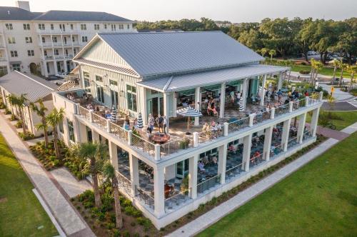 A modern building with a large outdoor patio, surrounded by palm trees and people enjoying the space.