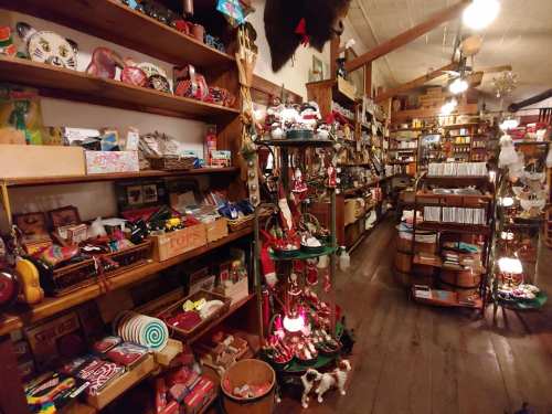 A cozy shop filled with colorful crafts, souvenirs, and decorations on wooden shelves and displays.