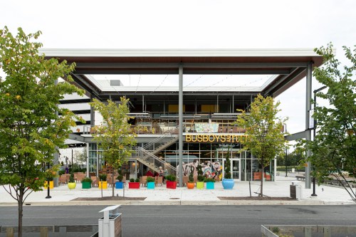 Exterior view of Busboys and Poets, featuring colorful planters and a modern architectural design.