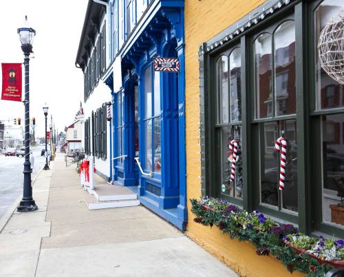 Colorful storefronts decorated for the holidays, featuring candy canes and festive greenery along a charming street.