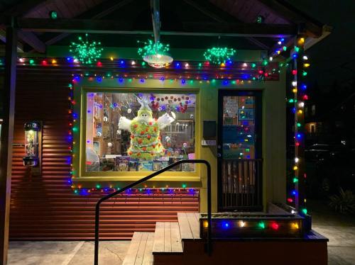 A brightly decorated house with colorful lights and a large snowman in the window, set against a night sky.