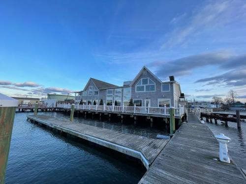 A waterfront building with large windows, situated on a dock, under a blue sky with scattered clouds.