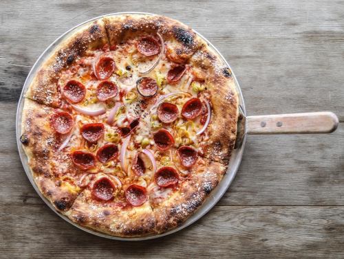 A freshly baked pepperoni pizza on a wooden table, with a golden crust and melted cheese.