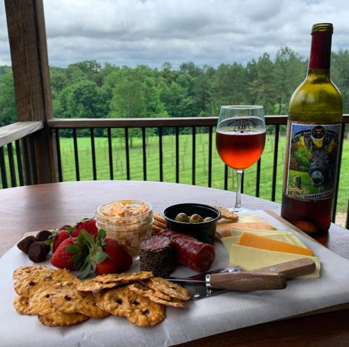 A charcuterie board with cheese, crackers, fruit, and a glass of wine, set against a scenic outdoor backdrop.