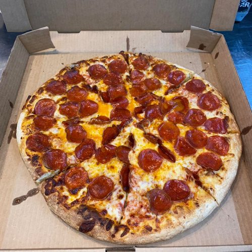 A large pepperoni pizza with melted cheese, cut into slices, in an open pizza box.