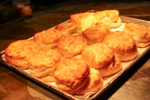 A tray of freshly baked, golden-brown biscuits arranged neatly on parchment paper.