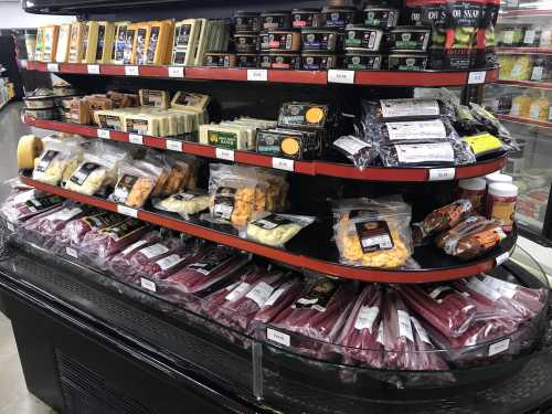 A display case filled with various cheeses, meats, and packaged snacks in a grocery store.