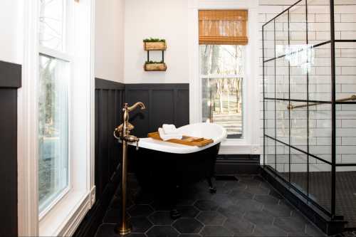 A stylish bathroom featuring a black freestanding tub, wooden accents, and a glass shower enclosure with natural light.