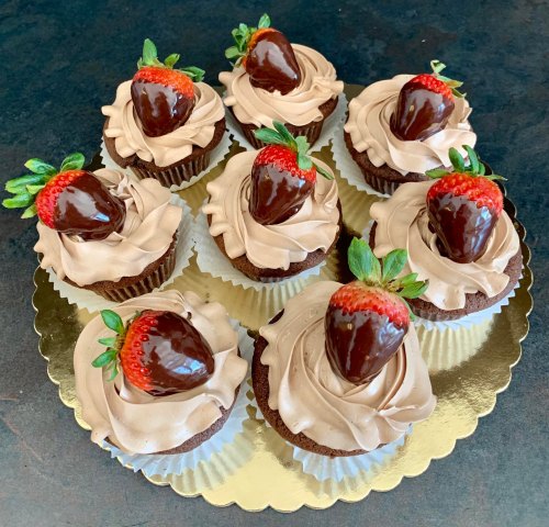 A platter of chocolate cupcakes topped with chocolate-dipped strawberries and swirls of chocolate frosting.
