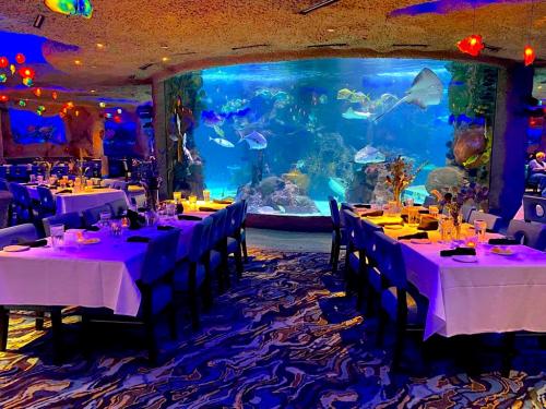 A vibrant restaurant with tables set for dining, featuring a large aquarium filled with colorful fish and rays.