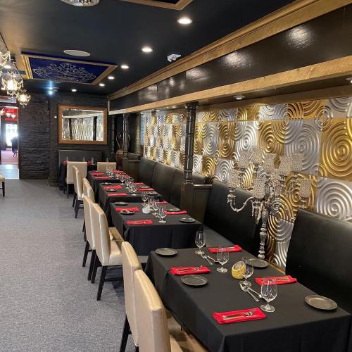Elegant restaurant interior with black tables, gold accents, and decorative mirrors, set for dining.