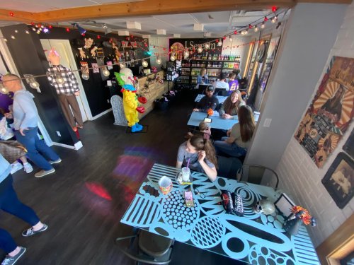 A lively café scene with colorful decor, people socializing, and a clown figure in a playful atmosphere.