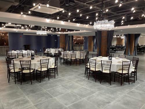 Elegant dining area with round tables, white tablecloths, and chandeliers, set for an event.