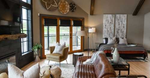 Cozy modern bedroom with a large window, stylish furniture, and a view of the outdoors. Warm, inviting decor.