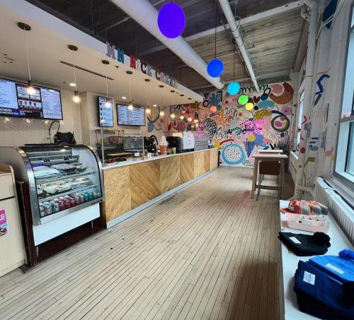 Brightly colored café interior with a counter, display case, and playful wall art. Wooden floors and modern decor.
