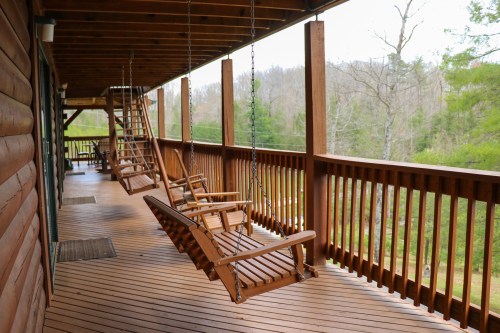 A wooden porch with hanging swings, surrounded by trees and a peaceful outdoor view.