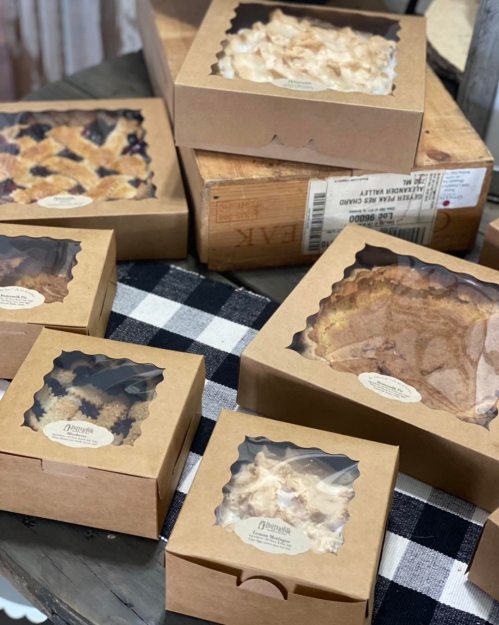 A variety of baked goods in decorative boxes displayed on a checkered tablecloth.