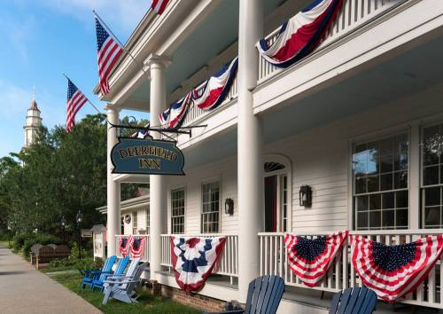 Exterior of Deerfield Inn decorated with American flags and bunting, featuring blue adirondack chairs on the porch.