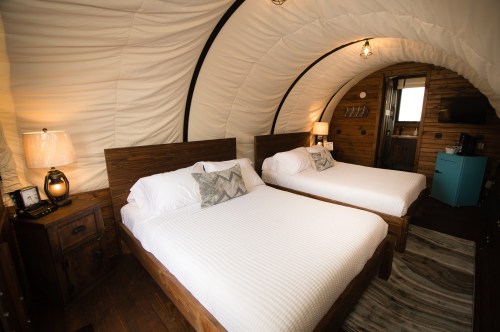 Cozy interior of a cabin with two beds, wooden accents, and soft lighting, creating a warm atmosphere.