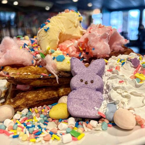 A colorful dessert stack with waffles, ice cream, cotton candy, sprinkles, and a purple marshmallow bunny.