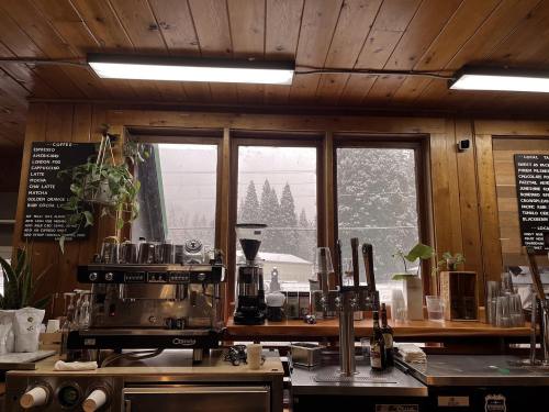 Cozy coffee shop interior with a wooden ceiling, espresso machine, and snowy landscape visible through large windows.