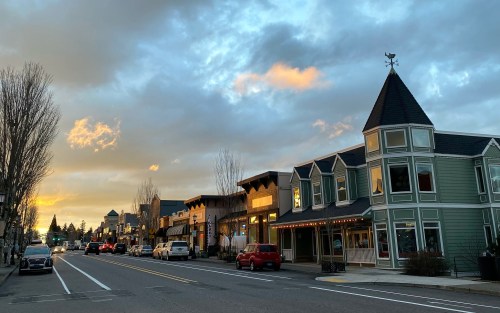 A charming street scene at sunset, featuring quaint buildings and a cloudy sky with hints of orange and blue.