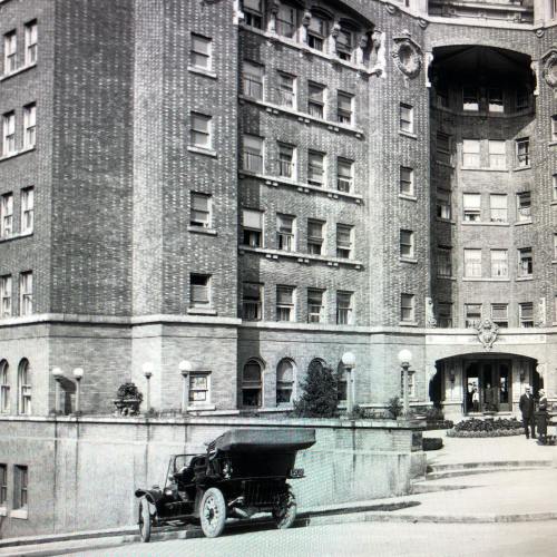 Historic building with large windows, a decorative entrance, and an early 20th-century car parked in front.