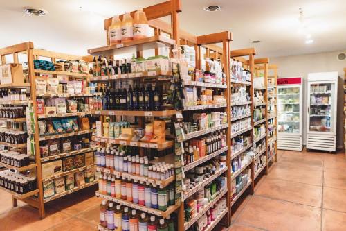 A well-stocked health food store with wooden shelves filled with various products and a refrigerator in the background.