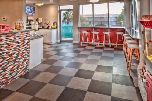 Bright, modern café interior with colorful tiled counter, bar stools, and a popcorn machine. Large windows let in natural light.