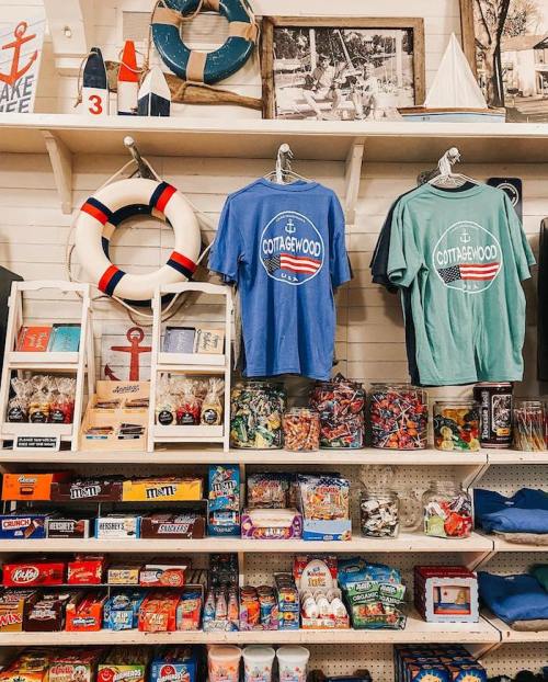 A colorful display of souvenirs, including t-shirts, candy, and games, in a quaint shop with nautical decor.