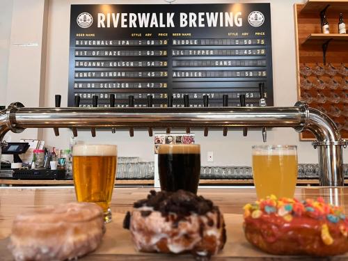 A brewery counter with a menu board, featuring beer options and three colorful donuts in the foreground.