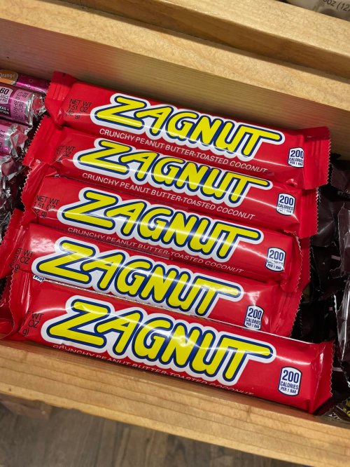 A wooden drawer filled with Zagnut candy bars, featuring bright red packaging and text highlighting peanut butter and coconut.