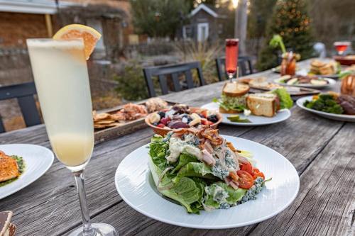 A table set outdoors with a variety of dishes, featuring a salad, drinks, and a festive atmosphere.