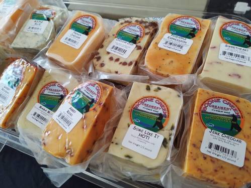 A variety of packaged cheeses with colorful labels, displayed in a neat arrangement.