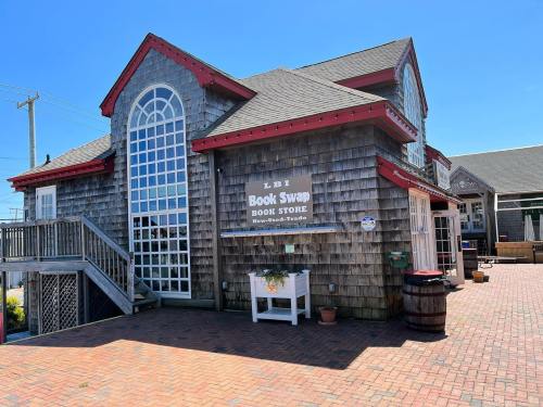 A charming book store with a shingled exterior, large windows, and a welcoming entrance on a sunny day.