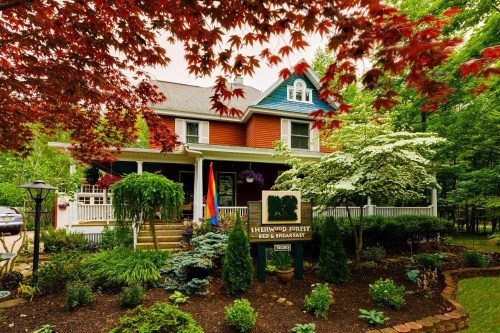 A charming bed and breakfast surrounded by lush greenery and colorful flowers, featuring a welcoming sign and vibrant decor.