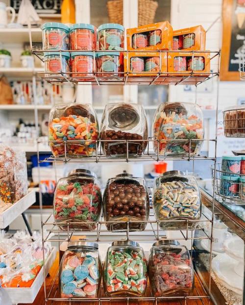 A display rack filled with various jars of colorful candies and treats in a charming shop setting.