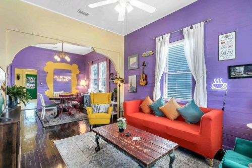 Cozy living space with purple walls, colorful furniture, and a dining area, featuring a mix of modern and vintage decor.