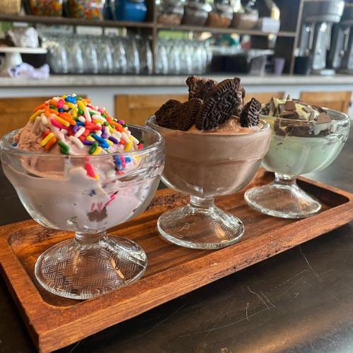 Three ice cream scoops in glass bowls: one with sprinkles, one chocolate with Oreos, and one mint chocolate chip.