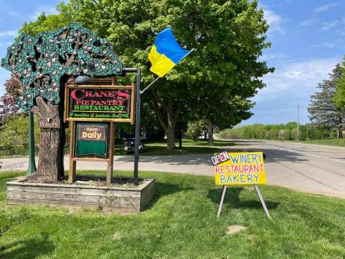 Sign for Crane's Pie Pantry Restaurant with a Ukrainian flag, indicating it's open for dining and bakery services.