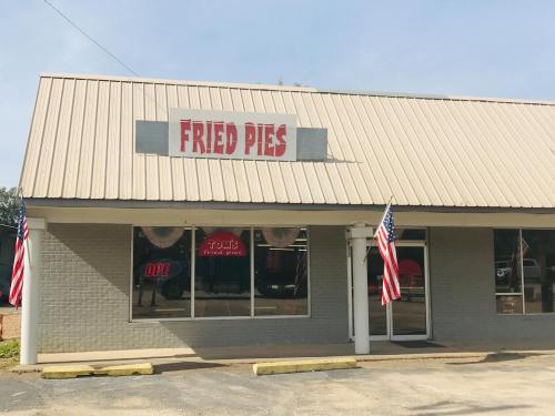Exterior of a shop named "Fried Pies," featuring American flags and a welcoming sign in the window.