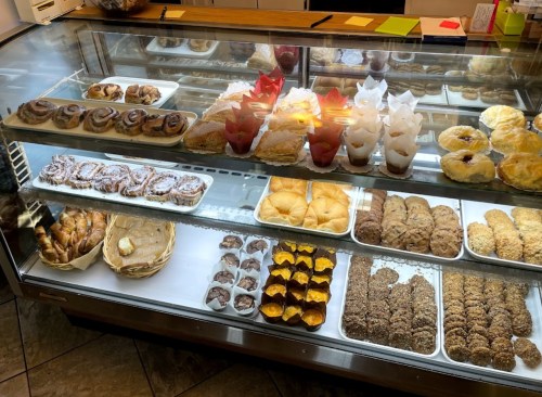 A display case filled with various baked goods, including pastries, cookies, and cinnamon rolls.