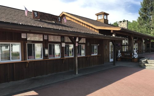 A wooden ice cream shop with a sign reading "Rich Farm Ice Cream" and a menu displayed in the windows.