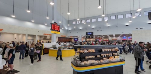 A busy food court with various dining options and a crowd of people enjoying their meals.