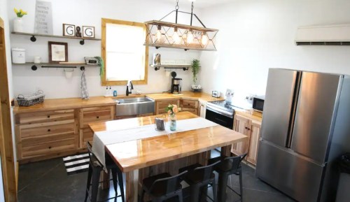 A modern kitchen with wooden cabinets, a large island, stainless steel appliances, and a bright, airy atmosphere.
