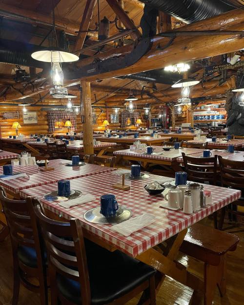 Cozy restaurant interior with wooden decor, checkered tablecloths, and set tables ready for dining.